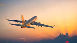 A person's hands writing in a travel journal with a map and compass